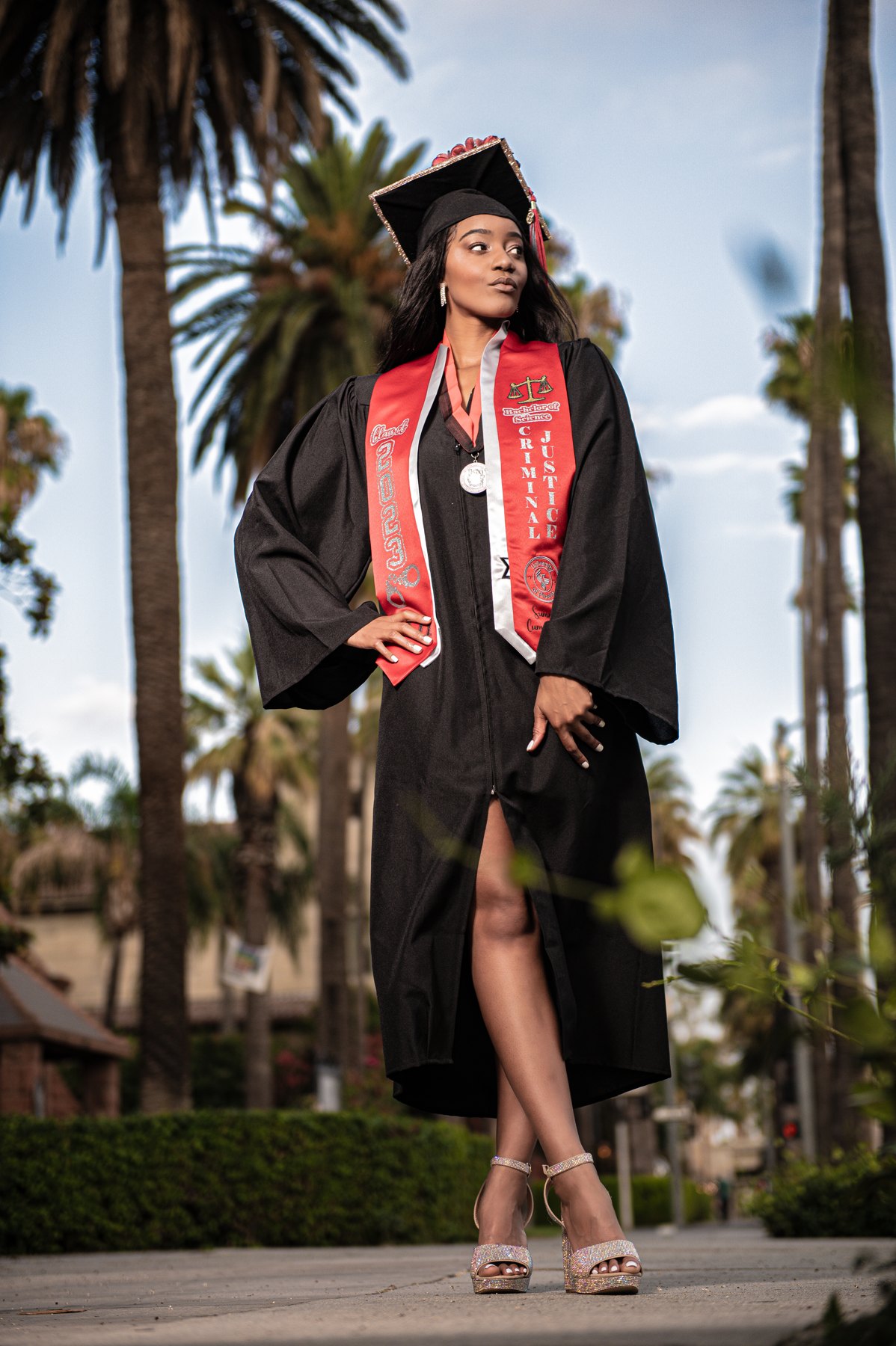 Graduate photographed outdoors beneath palm trees